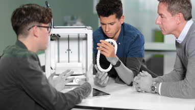 Students discussing 3D printer with teacher