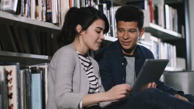Students using digital tablet in library