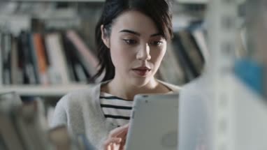 Student using digital tablet in library