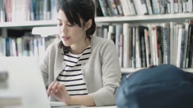 Student studying in library with laptop
