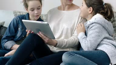 Mom and daughters looking at digital tablet