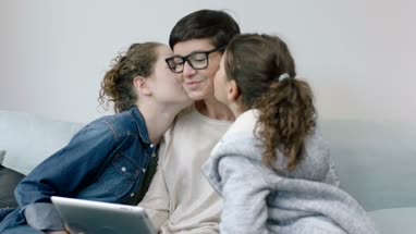 Daughters kissing Mom on cheek
