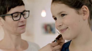 Mom plaiting daughters hair