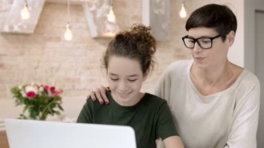 Mom helping checking daughter homework on laptop