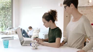 Mom helping checking daughter homework on laptop