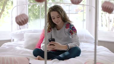 Teenager using smartphone in bedroom