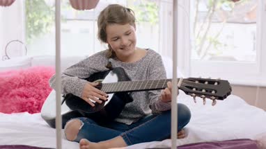 Girl learning to play guitar in her room