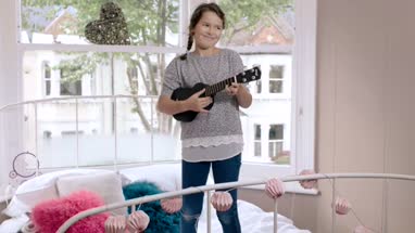 Girl playing ukulele in her room