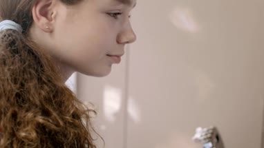 Teenager learning to play guitar in her room