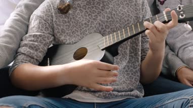Girl playing ukulele and singing with family