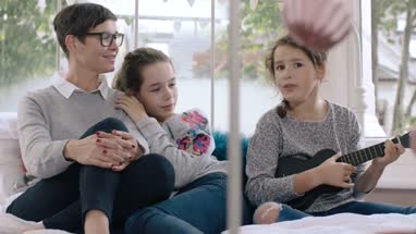 Girl playing ukulele and singing with family