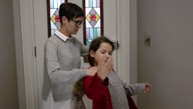 Mom helping daughter put warm winter coat on