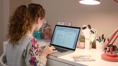 Teenager working on homework on laptop