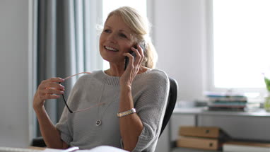 Mature business woman working on desktop computer and smartphone