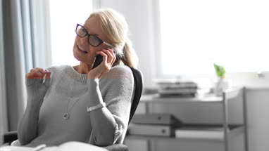 Mature business woman working on desktop computer and smartphone