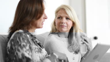 Mature female friends looking at digital tablet
