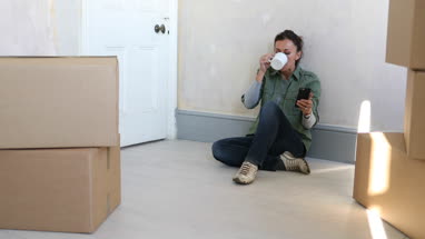 Mature female using smartphone with moving boxes