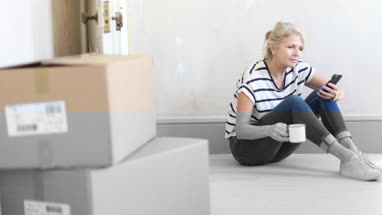 Mature female using smartphone with moving boxes