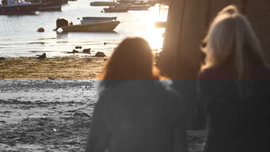 Mature female friends walking down to harbour