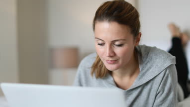 Young adult female using laptop in bed