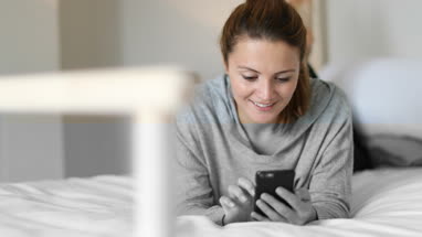Young adult female using smartphone in bed