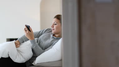 Young adult female waking up and using smartphone