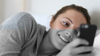 Young adult female using smartphone in bed