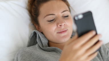 Young adult female using smartphone in bed