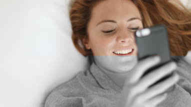 Young adult female using smartphone in bed