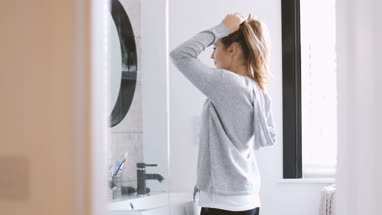 Young adult female looking in bathroom mirror