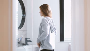 Young adult female looking in bathroom mirror
