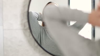 Reflection of young adult female looking in bathroom mirror