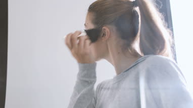Young adult female looking in mirror putting make-up on 