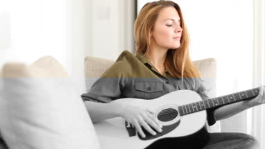 Young adult female playing acoustic guitar