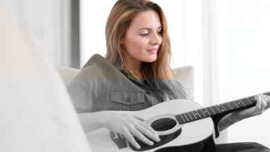 Young adult female playing acoustic guitar