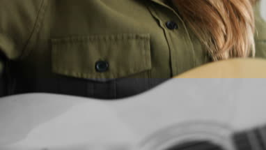 Young adult female playing acoustic guitar