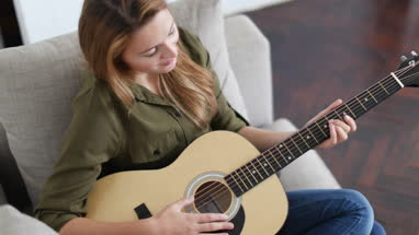 Young adult female playing acoustic guitar
