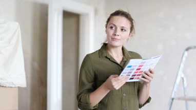 Young adult female choosing colour to paint wall