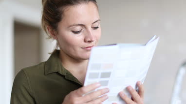 Young adult female choosing colour to paint wall