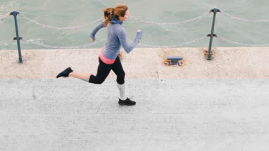 Young adult female running outdoors by sea