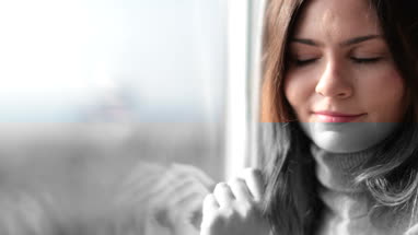 Woman looking out of window in morning light