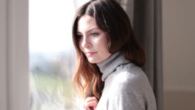 Woman looking out of window in morning light