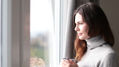 Woman looking out of window with morning coffee