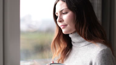 Woman looking out of window with morning coffee