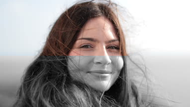 Carefree woman with wind in her hair looking to camera