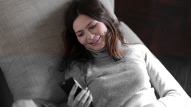 Woman laughing at message on smartphone