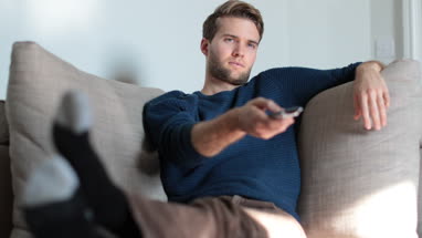 Man watching TV at home on sofa