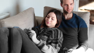 Couple relaxing on sofa at home watching TV