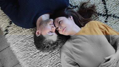 Couple lying down on rug in new home