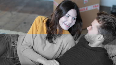 Couple lying down on rug in new home